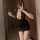 Woman wearing a black lace bodycon dress with a deep neckline, taking a mirror selfie.