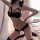 Woman modeling black lace 3-piece lingerie set with open-crotch design, pink bows, and sheer stockings for intimate moments.