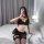 Woman wearing black yan yan sexy lingerie set with lace bra, ruffled shorts, and stockings on bed.