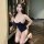 Woman kneeling in a navy blue premium sheer milk silk bodysuit with white trim and spaghetti straps.