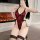 Woman wearing red qqny sensual lingerie with black lace trim, gold foil accents, and fishnet stockings in front of fireplace.