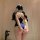 A woman stands facing away from the camera, wearing a midnight blue bodysuit with white lace detailing on the straps. the des...