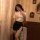 A woman poses elegantly in a vintage-themed setting, wearing a white blouse with gold buttons and a black mini skirt featurin...