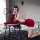 A person poses playfully on a chair wearing a festive christmas-themed sleepwear set, featuring a red mini skirt with white f...