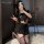 A woman poses with a smartphone, wearing a black schoolgirl-style pleated mini skirt paired with stockings. the outfit featur...