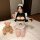 A woman wearing a yasu cosplay maid costume, featuring a cute anime-style sexy sleepwear and roleplay uniform, sitting on a b...