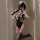 A woman poses in a black lace maid costume with stockings, capturing a playful moment. the outfit features delicate lace deta...