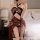 A woman poses in a sheer lace bondage nightwear set, featuring a halter top and thigh-high skirt, designed for sensual allure...