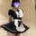 A woman wearing a black and white maid costume set, featuring a ruffled apron and short sleeves, posing indoors.