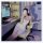 A woman lounges in a gaming chair wearing a floral lace contrast sexy low-cut slip dress made from pure temptation satin-blen...