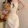 A woman holds a teddy bear while wearing a cream cherry print cami slip dress with lace trim and built-in pads, exuding elega...