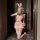 A woman poses in a playful bunny-themed outfit, featuring a pink bustier set with lace details and thigh-high stockings, hold...