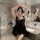 A woman poses in a luxurious bathroom wearing a black lace chemise, featuring sheer fabric and elegant design, perfect for ro...