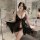 A woman poses in a luxurious bathroom wearing a sheer black lace chemise, part of a romantic lingerie set designed for couple...