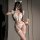 A woman poses in a white catwoman-themed lingerie set featuring cat ears, fluffy bows, and fishnet stockings, holding a teddy...