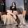 A stylish woman poses on a cozy chair wearing elegant black thigh-high stockings with sheer fabric and lace trim details, exu...