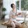 A woman poses elegantly on a table wearing a sheer white long night set with black trim, featuring a stylish design perfect f...