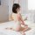 A woman sits on a bed wearing a white swimsuit with a backless design, highlighting its stylish and comfortable fit for summe...