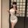 A woman poses in a white lace embroidered sheer bodycon dress, perfect for a sexy date night. the mini dress features intrica...