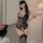 Woman wearing black lace bodysuit with sheer panels and floral embroidery, paired with matching thigh-high stockings.