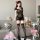 Woman wearing black lace mesh see-through bodycon mini dress with cutout corset top and matching thigh-high stockings.