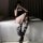 A person wearing y2k-style black stockings with over-the-knee fishnet design, paired with platform heels, sitting on a bed.