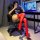 Woman wearing lace trim thigh-high stockings with red band, sitting on gaming chair next to anime-themed desk setup.