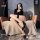 A stylish woman poses on a cozy chair wearing elegant black thigh-high stockings with sheer fabric and lace trim details, exu...