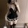 Woman wearing black and white maid costume with lace trim, backless design, bow accents, thigh-high stockings, and feather du...
