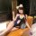 Woman in navy blue adorable dog bone lace bodysuit with cut-outs, white trim, and fluffy ears, posing on a leather chair.