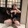 Woman in navy blue dog bone lace bodysuit with sexy cut-outs, white trim, and matching accessories, posing playfully indoors.