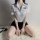 Woman wearing airu airu sexy flight attendant costume with short skirt and white shirt, sitting on a fluffy rug.