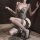 Woman in american style mesh leopard print bodysuit with fishbone detailing, posing seductively with a whip.