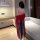 Woman wearing red hanfu doudou and sheer embroidered flying skirt, back view in modern room.