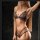 Woman wearing black lace thong set with sheer bra and elegant choker, stylish sleepwear for women at home.