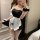 Woman in black lace bunny maid costume with white apron and fishnet stockings, posing for selfie.