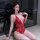 Woman wearing red lace mesh bodysuit with deep v-neck and halter straps, posing by window at night.