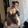 Woman wearing black lace open-crotch fishnet bodysuit with rhinestones, posing seductively in mirror selfie.