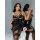 Model wearing black patent leather lace-up lingerie set with cutout bra and panty, sheer stockings.