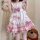 A woman wears a cute pink maid outfit with ruffles, bows, and paw prints, perfect for cosplay or lolita fashion.