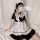 A woman poses wearing a black and white maid dress, featuring ruffled sleeves and collar, perfect for cosplay or lolita fashi...