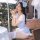 A woman wearing a blue grid maid costume, featuring a playful open-crotch design, sits outdoors holding a sandwich. the outfi...