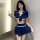 A woman poses wearing a blue sailor uniform lingerie set featuring a bow top and pleated skirt, perfect for nightclub or role...