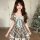 A charming woman wears a vintage-inspired plaid dress with lace detailing and a bow at the waist, perfect for summer elegance...