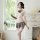 Woman in sheer british-style lace teddy set with jk pleated skirt, bow tie, and thigh-high stockings holding a book.