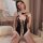 Woman wearing black bunny girl lingerie bodysuit with white lace trim, bow ties, and open-crotch design.