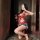 Woman wearing red butterfly bow bodysuit with lace and open-crotch design, paired with denim shorts, holding wine glass in mi...