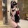 Woman wearing black butterfly knot maid apron set with red bow, lace trim, and garter stockings in luxury bathroom.