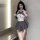 Woman wearing backless butterfly lace bodysuit, cute sexy jk uniform style, kneeling on bed with sheer lace detailing.