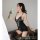 A woman poses elegantly holding white flowers, wearing a black lace lingerie set with sheer stockings and matching panties, d...